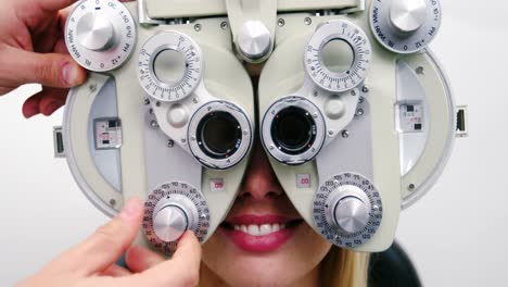 optometrist examining female patient on phoropter