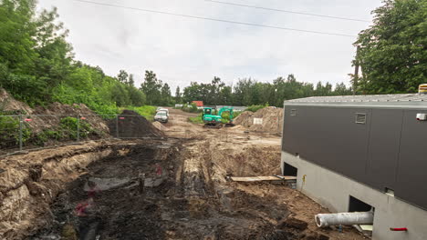 workday of small digger, trucks and crane in construction site, fusion time lapse