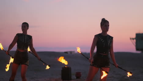 Frauen-Mit-Feuer-Bei-Sonnenuntergang-Auf-Dem-Sand-Tanzen-Und-Zeigen-Tricks-Vor-Dem-Wunderschönen-Himmel-In-Zeitlupe