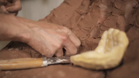 un primer plano de las manos de los alfareros moldeando arcilla. un artista crea una escultura de cerámica de la mano humana utilizando una herramienta profesional. tiro de enfoque selectivo