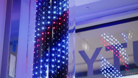 A-neon-barber-pole-turns-on-inside-a-barber-shop-and-twirls-in-red-and-blue-colours-against-a-business-window