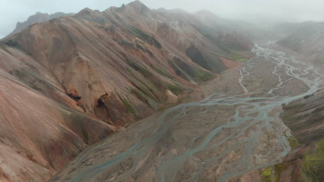 aerial view revealing rugged mountains, river valley, landmannalaugar, iceland