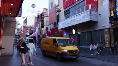 people walking and a dhl van passing