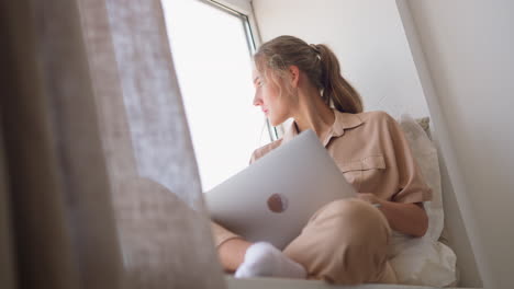 lady young copywriter looks through window working on laptop