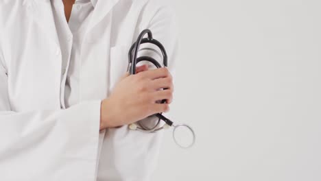 Video-of-biracial-female-doctor-holding-stethoscope-on-white-background