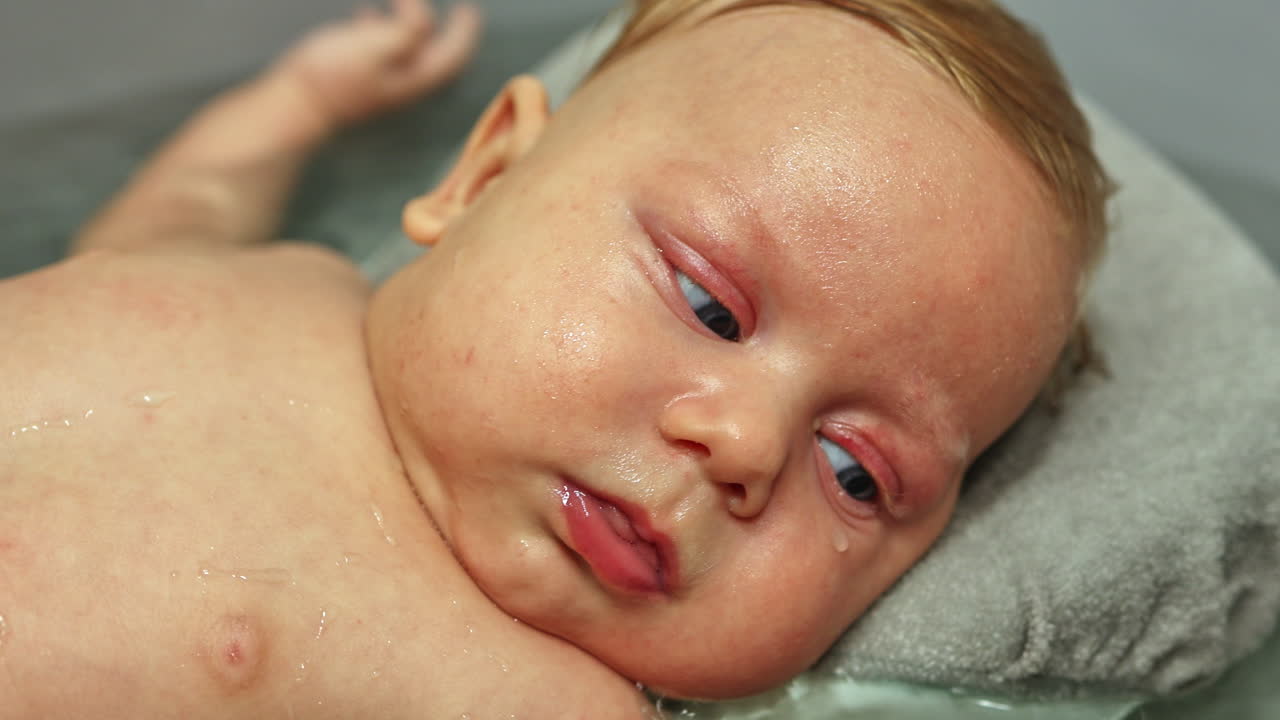 O bebê está na água no banheiro. Cuidado com a higiene pessoal do bebê. A criança toma banho em água morna deitada no suporte.