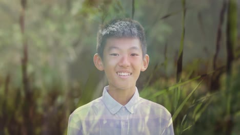 animation of smiling asian boy over moving grass