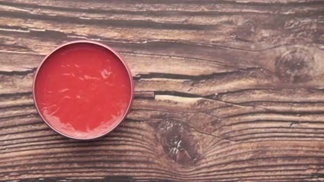 pink container of red lip balm on a wooden table