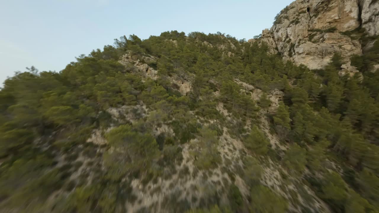 Fpv Drone view of cliffs and sailboats docked along seaside in Cala d'egos beach