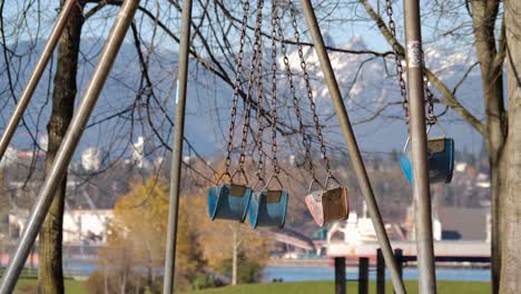 empty playground swings blowing gently in the wind - sunny day in park