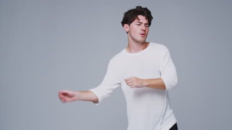 wide angle studio shot of young man against white background dancing in slow motion