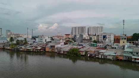 Canal-with-rustic-shanty-houses-and-new-development-in-Ho-Chi-Minh-City-Vietnam-evening-drone-video