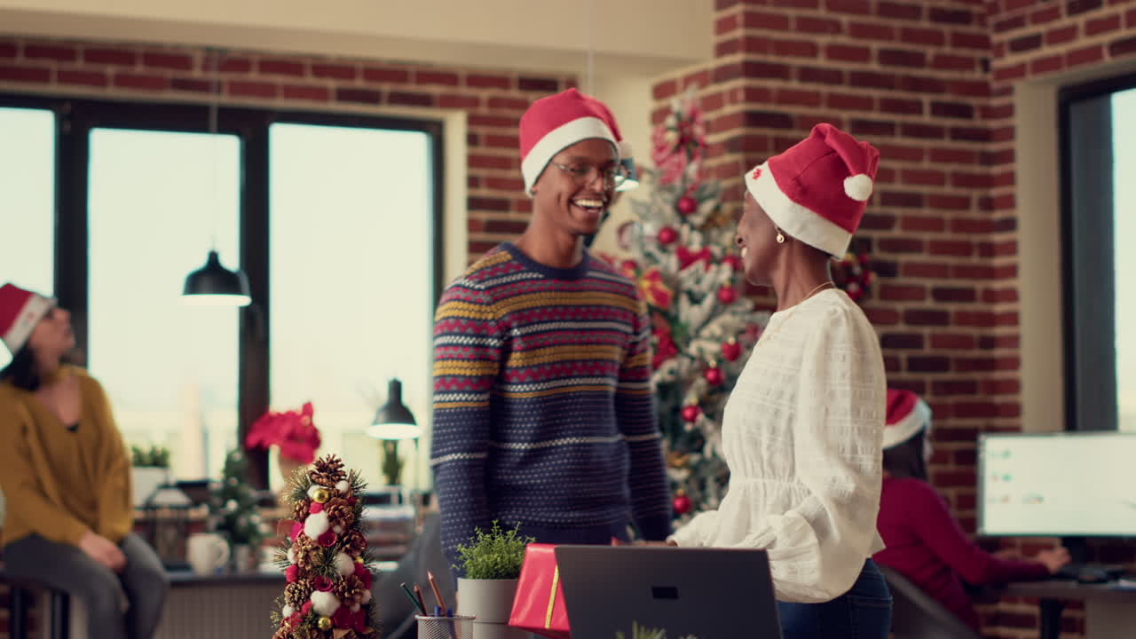 Colleagues with santa hats exchanging presents during xmas eve