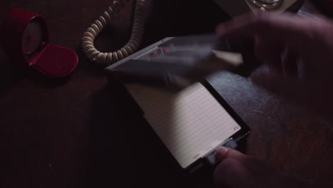 the hand of a person in a white shirt is working with a phone book and then making a phone call on a dial phone