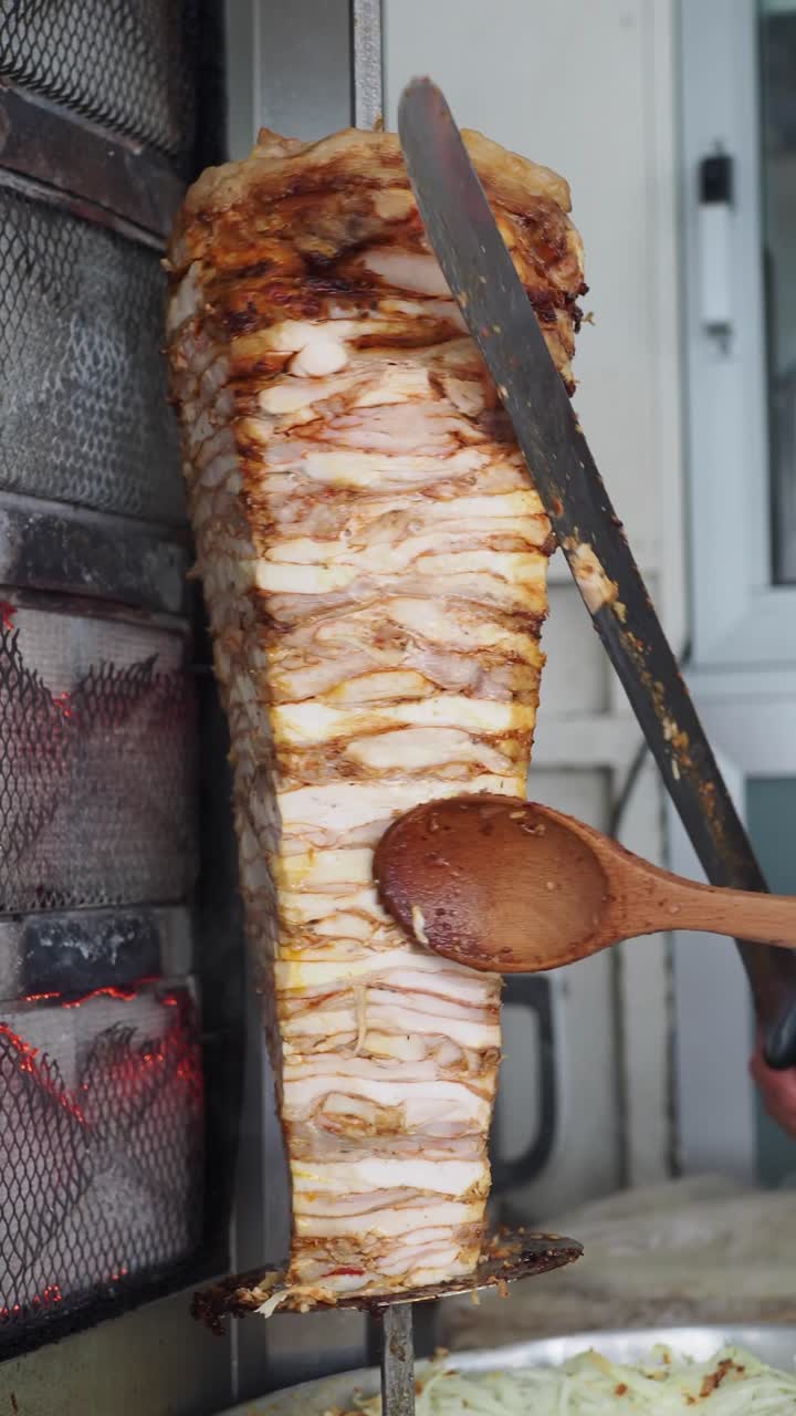 Chef affetta deliziosa carne di Doner Kebab dal girarrosto verticale