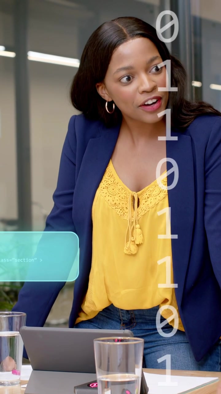 Vertical video: Team lead leaning on table tapping tablet, causing teal binary UI during tech brief
