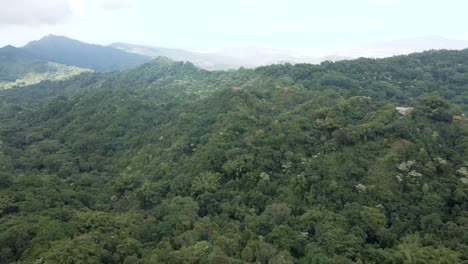 Drone-aerial-shot-over-the-luscious-green-forest-mountains-of-the-Sierra-Nevada,-in-Colombia,-gradually-approaching-and-circling-a-lone-house-on-a-hill