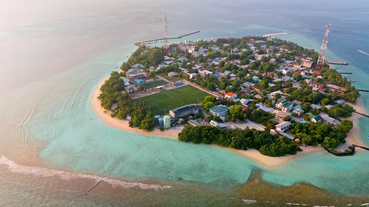 A breathtaking aerial drone view captures Rasdhoo Island bathed in the warm glow of sunset in the Maldives.