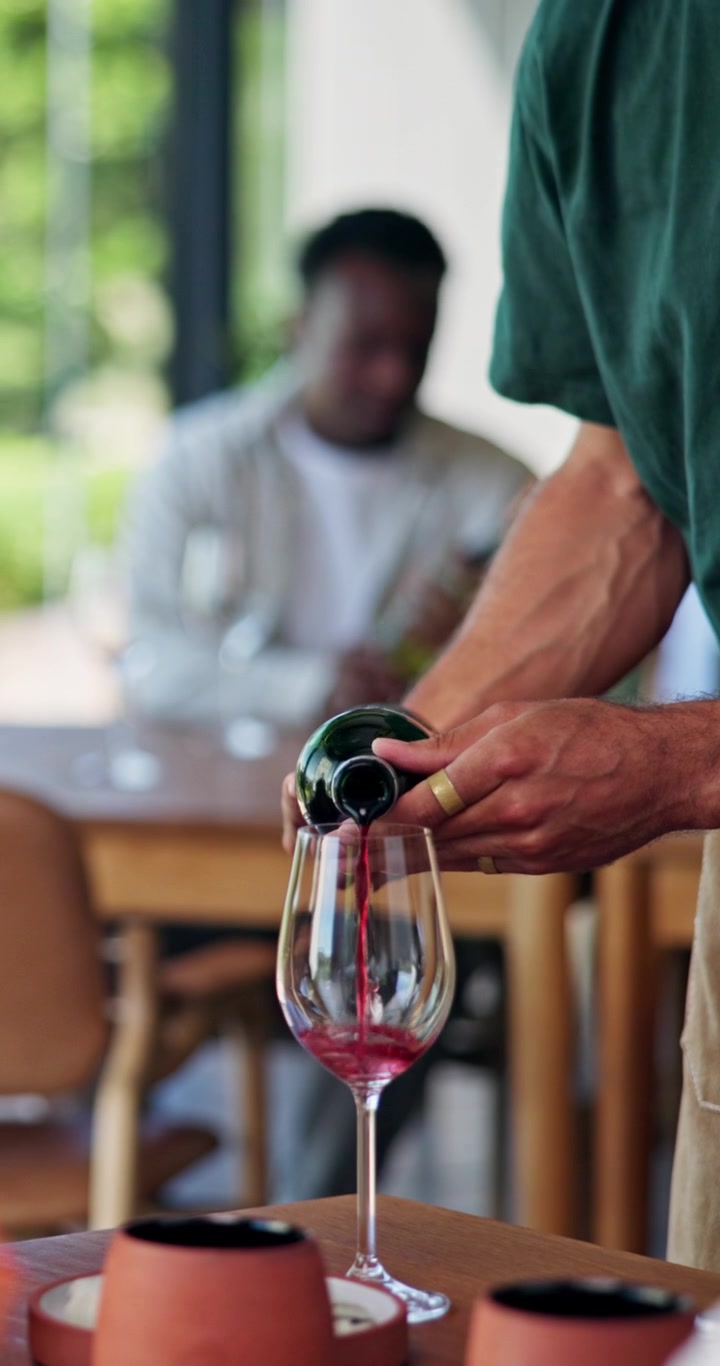 Cameriere che versa vino rosso in un bicchiere al ristorante
