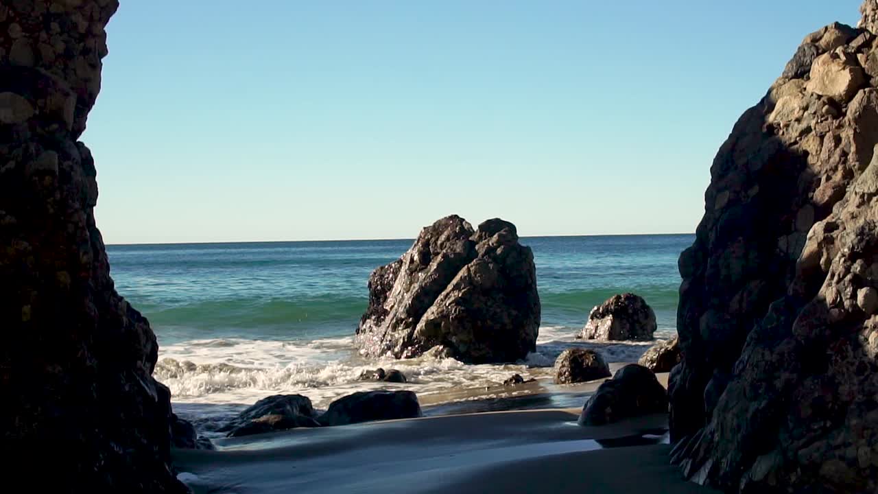 olas en cámara lenta chocando contra las rocas que sobresalen en malibu, california