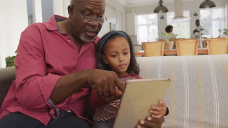 Video-Eines-Glücklichen-Afroamerikanischen-Großvaters-Und-Seiner-Enkelin,-Die-Gemeinsam-Ein-Tablet-Nutzen