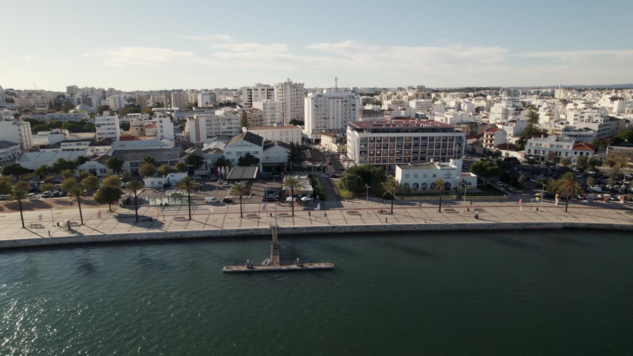 Orbita aerea sopra il lungomare di Portimão, sole che si riflette sul fiume Arade, edifici della città - Algarve.