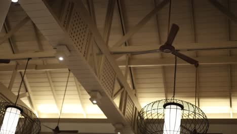 una serie de ventiladores de techo giran lentamente en un restaurante bien iluminado, creando una atmósfera tranquila y relajada