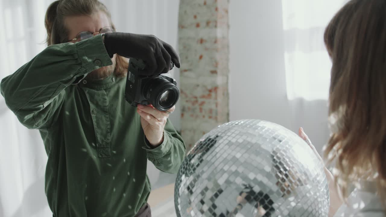 Professional Photographer Taking Pictures of Model with Disco Ball in Studio