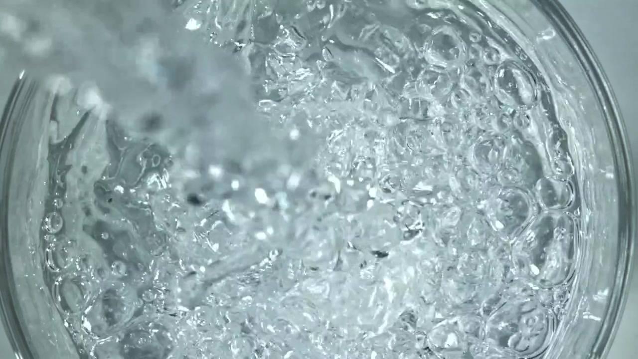 Acqua limpida che si versa in un bicchiere con bolle