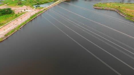 reveal drone shot birds-eye view camera roll up transmission tower power grid power line by the lake over the mountain