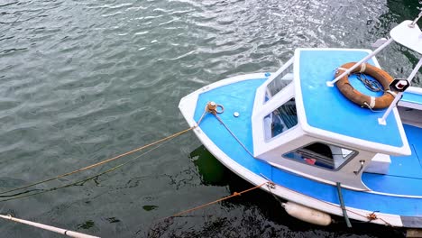 a blue boat gently sways in water