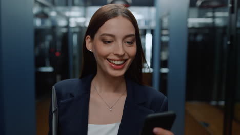 excited woman looking smartphone in office. lady reading message in corridor