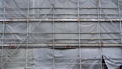 building covered with scaffolds and grey mesh