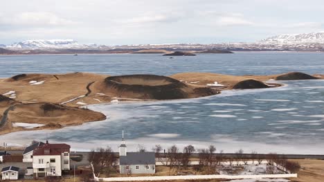 aerial of reykjahlíð church facing frozen mývatn lake and volcanic craters near skútustaðir iceland