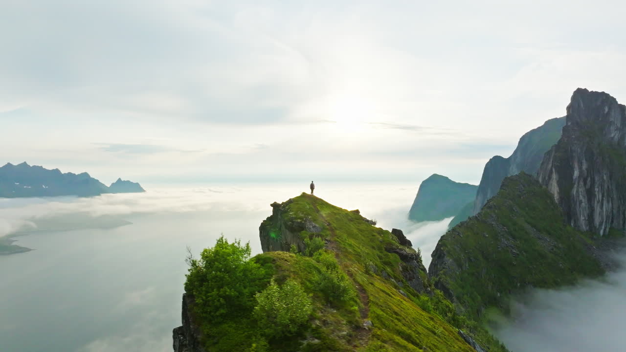 Hiker on majestic arctic Senja mountain ridge with spectacular view; drone