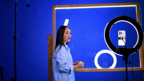 studio-working creative artist. a person in a blue shirt engages in artistic creation, surrounded by studio equipment and bright lighting elements