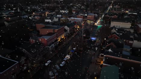 aerial pullback reveals town square during winter snow at night