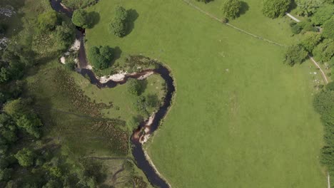 Toma-De-Un-Dron-De-Un-Río-Que-Fluye-A-Través-De-Un-Prado-Verde