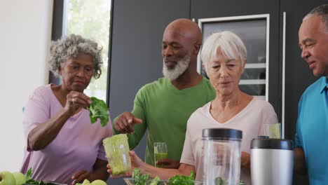 Happy-senior-diverse-people-making-healthy-drink-in-kitchen-at-retirement-home