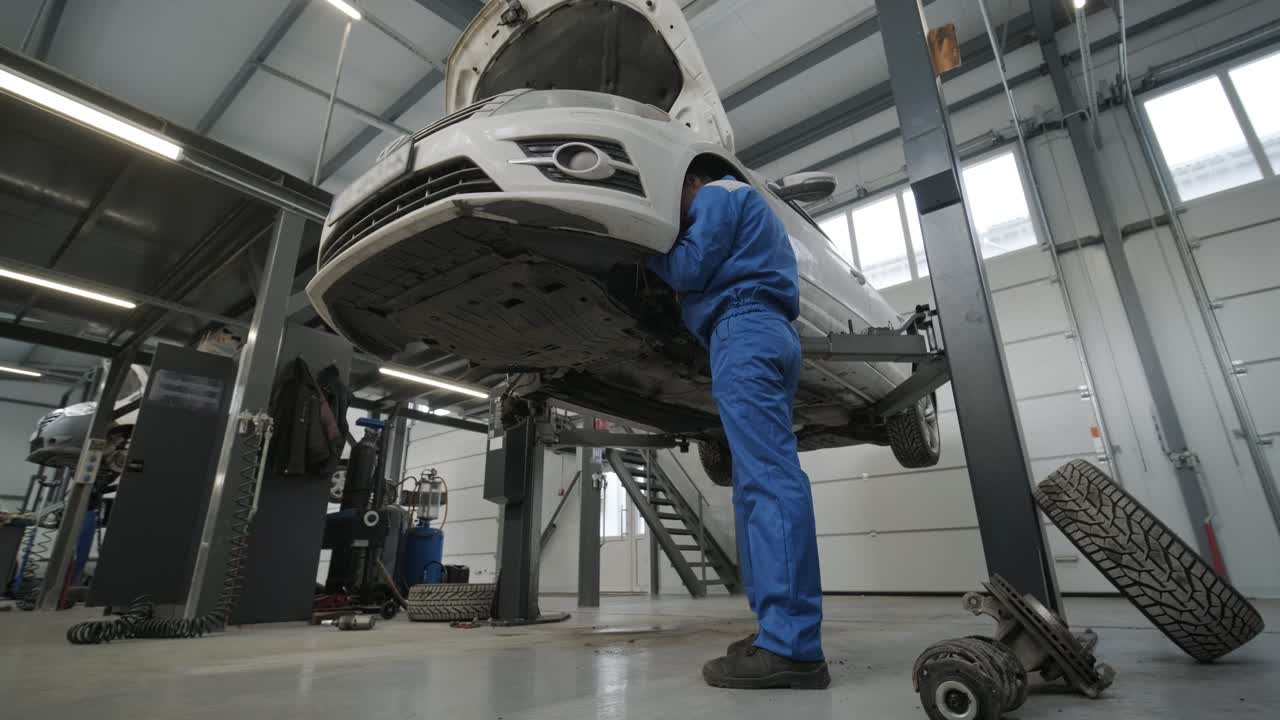 mecánico de automóviles reemplazando las patas de freno de la rueda del automóvil levantado en la estación de servicio de reparación