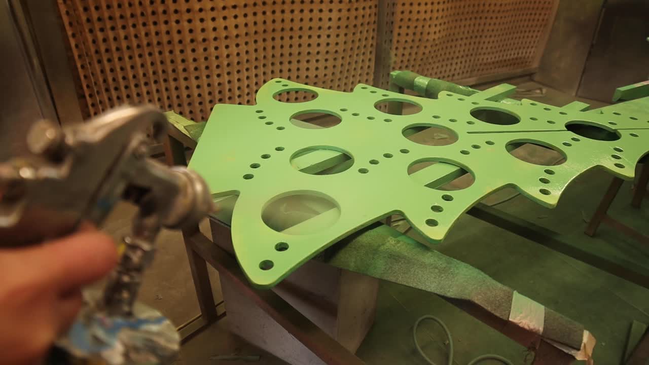 maestro de cultivos con pistola de pintura pintando un árbol de metal ornamental