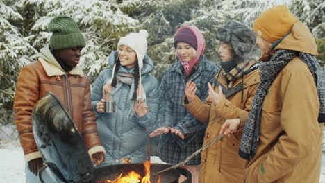 company of friends having picnic in woods on winter day