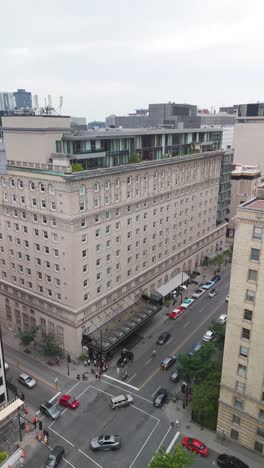 top-down aerial drone shot of a historic luxury hotel in downtown area. classic architecture with a striking modern rooftop addition, surrounded by dense urban scenery. vertical shot 9:16.