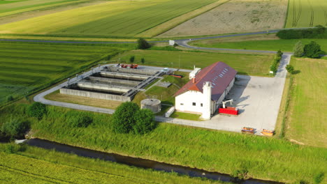 Aerial-view-of-small-sewage-treatment-plant-with-wastewater-tanks-and-filters,-fields-with-crops-surrounding-the-plant,-Slovenska-Bistrica,-Slovenia