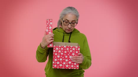 Elderly-granny-woman-opening-gift-box-expressing-disappointment,-dislike-gesture-to-awful-present