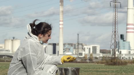 trabalhador de laboratório é campo de amostragem de solo com fábrica de energia em segundo plano