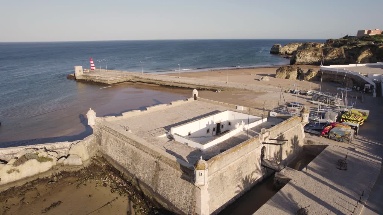 antena del antiguo fuerte en lagos, portugal durante la hora dorada mientras las palmeras imprimen sus sombras en las murallas históricas