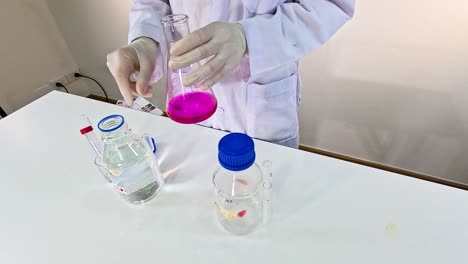 Scientist performs a potassium permanganate reduction experiment in a laboratory setting with controlled lighting and precise movements