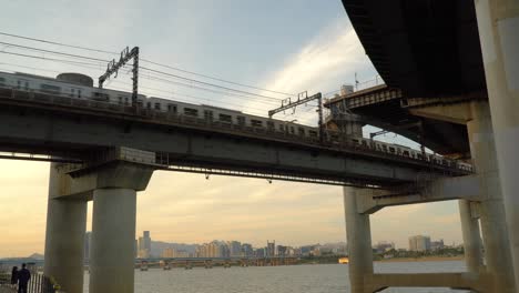 subway train crossing the cheongdam bridge across han river on sunset in seoul, south korea - low angle, static shot