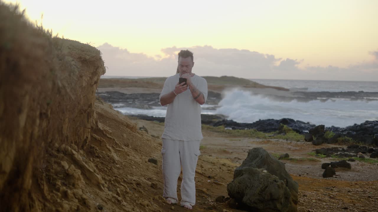 Man using smartphone on a beach at sunset